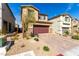 Two-story home with a two-car garage featuring a landscaped front yard and a brick paved driveway at 10922 Cambridge Lakes Ave, Las Vegas, NV 89166