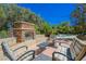 Cozy outdoor patio featuring a stone fireplace, seating, and a view of the lush backyard with mature trees and privacy at 11 Belfair Ct, Henderson, NV 89052