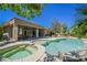 Inviting pool and spa area surrounded by lush greenery, lounge chairs, and an outdoor dining set for relaxation at 11 Belfair Ct, Henderson, NV 89052