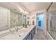 Bathroom with a blue vanity, quartz countertops, dual sinks, and glass-enclosed shower and tub at 2825 E Hacienda Ave, Las Vegas, NV 89120