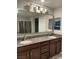 Stylish bathroom featuring a double vanity with granite countertops, dark wood cabinets, and a large framed mirror at 2829 Mozia Ct, Henderson, NV 89044