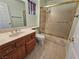 Bathroom with wood cabinets, marble countertop and tiled flooring and bathtub with glass door at 3104 Archwood Way, Las Vegas, NV 89134