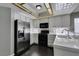 Bright kitchen with stainless steel refrigerator, black oven, white cabinets, and dark wood-look flooring at 4421 Rodman Dr, Las Vegas, NV 89130