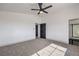 Well lit bedroom features a ceiling fan, gray carpet and baseboards, and modern black doors at 4473 Oberlander Ave, North Las Vegas, NV 89031