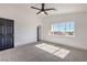 Bright bedroom featuring a ceiling fan, large window, neutral carpet and trim, and black door at 4473 Oberlander Ave, North Las Vegas, NV 89031