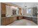 A spacious bathroom featuring double sinks, a walk-in shower, and a bathtub under a chandelier at 4925 Turtle Point Dr, Las Vegas, NV 89113