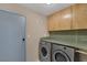 Bright laundry room featuring a washer, dryer, storage cabinets, and a gray door at 4925 Turtle Point Dr, Las Vegas, NV 89113