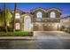 Exterior of a two story home with a three car garage, arched entry and manicured lawn at 62 Incline Village Ct, Henderson, NV 89074