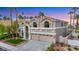 Two-story home featuring a three-car garage, arched windows, and desert landscaping at 62 Incline Village Ct, Henderson, NV 89074