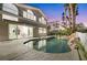 A backyard pool with a rock waterfall feature, patio, and view of a two-story home with large windows at 62 Incline Village Ct, Henderson, NV 89074