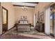 Cozy main bedroom features stylish furniture, a chandelier, beamed ceiling, and lots of natural light at 6760 Hinson St, Las Vegas, NV 89118