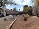 Spacious backyard featuring a brick retaining wall, mature trees, and a gravel landscape at 710 Strawberry Pl, Henderson, NV 89002