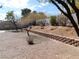 Large backyard featuring a brick retaining wall, mature trees, and a gravel landscape at 710 Strawberry Pl, Henderson, NV 89002