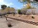 Spacious backyard featuring a brick retaining wall, mature trees, and a gravel landscape at 710 Strawberry Pl, Henderson, NV 89002