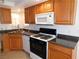 Well-maintained kitchen featuring wooden cabinets, granite countertops, and modern white appliances at 710 Strawberry Pl, Henderson, NV 89002