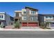 Striking three-story home with modern design elements and a red two-car garage at 7180 Grace Estate Ave, Las Vegas, NV 89113