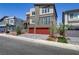 Modern three-story home with clean lines, a balcony, and a red two-car garage at 7180 Grace Estate Ave, Las Vegas, NV 89113