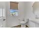 Powder room features a modern pedestal sink, toilet, and a window with natural light at 7180 Grace Estate Ave, Las Vegas, NV 89113