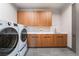 Well-lit laundry room features modern washer and dryer, with warm wood cabinets and solid surface countertop at 801 Dragons Eye Dr, Henderson, NV 89012