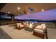 Comfortable seating area with fire pit for relaxing with outdoor dining and TV at dusk at 801 Dragons Eye Dr, Henderson, NV 89012