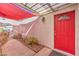 Inviting front entryway with a red door, covered porch, and mature desert landscaping at 8229 Willeta Ave, Las Vegas, NV 89145