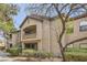 Exterior view of tan condo building with balconies, landscaped shrubs and gravel, set against a blue sky at 8250 N Grand Canyon Dr # 2102, Las Vegas, NV 89166