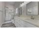 Bathroom featuring double sinks, quartz countertops, and tiled shower with glass enclosure at 832 Vineyard Vine Way, North Las Vegas, NV 89032