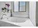 Close up of a white bathtub beneath a window, accompanied by decorative plants on the side at 854 Earth Luster Rd, Las Vegas, NV 89178