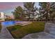 Backyard view of the pool and spa surrounded by green grass and mature trees with an iron fence at 8701 Robinson Ridge Dr, Las Vegas, NV 89117