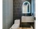 Stylish powder room features black tiled wall, a floating sink, and an illuminated arched mirror at 10313 Orkiney Dr, Las Vegas, NV 89144