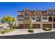 View of a three-story townhome with tan stucco, brown trim, and a brick driveway on a sunny day at 1092 Via Corto St, Henderson, NV 89011