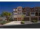 View of a three-story townhome with tan stucco, brown trim, and a brick driveway on a sunny day at 1092 Via Corto St, Henderson, NV 89011