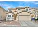 Beige two-story home featuring a two-car garage, desert landscaping, and a tiled roof at 1646 Little Crow Ave, Las Vegas, NV 89123