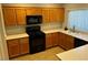 Cozy kitchen featuring wood cabinetry, black appliances, and neutral countertops at 3337 Autumn Veil St, Las Vegas, NV 89129