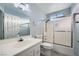 A bathroom with a white cabinet, toilet, large mirror, and a bathtub with sliding glass doors at 3675 Winner Dr, Las Vegas, NV 89120