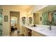 Bright bathroom featuring a double vanity, large mirror, and walk-in shower with marble surround at 5059 Pensier St, Las Vegas, NV 89135