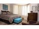 Comfortable bedroom featuring wood floors, shuttered windows, and a stylish blue ottoman at 5059 Pensier St, Las Vegas, NV 89135