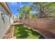 Spacious backyard with lush artificial grass, bordered by rocks, offering a private outdoor living space and enclosed by a brick wall at 5078 Shadow River St, Las Vegas, NV 89148