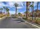 Gated community entrance with a well-maintained road, mature landscaping and tall palm trees adding to the curb appeal at 5078 Shadow River St, Las Vegas, NV 89148