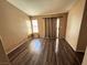 Bedroom with wood-look flooring, neutral walls, window with blinds, and sliding door access at 5513 Oakwood Ridge St, Las Vegas, NV 89130