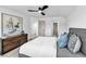 Bright bedroom features a grey upholstered headboard, modern ceiling fan, and wood dresser with abstract art at 7685 Spanish Bay Dr, Las Vegas, NV 89113