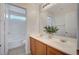 Bright bathroom with dual sink vanity, framed mirror, wood cabinets and a shower over bath at 8027 Anasazi Ranch Ave, Las Vegas, NV 89131