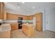 Well-lit kitchen features wood cabinets, black appliances, island, and tile backsplash at 8027 Anasazi Ranch Ave, Las Vegas, NV 89131