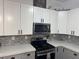 Well-lit kitchen features white upper cabinets and gray lower cabinets, stainless steel appliances, and gray subway tile backsplash at 807 Zinnia Cir, Henderson, NV 89015