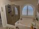 Relaxing bathroom with a soaking tub, glass-enclosed shower, and a sunny arched window at 9204 Gentle Cascade Ave, Las Vegas, NV 89178