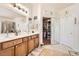 Bathroom featuring double sinks, wood cabinets, decorative mirrors, and walk-in closet at 9204 Gentle Cascade Ave, Las Vegas, NV 89178