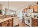 Well-lit kitchen featuring wood cabinets, white appliances, tile flooring, and breakfast bar at 9204 Gentle Cascade Ave, Las Vegas, NV 89178