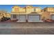 Modern townhome complex showcases garages, desert landscaping, and a stucco facade under a bright sky at 9564 Belle Fountain Ave, Las Vegas, NV 89123