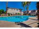 Outdoor community pool surrounded by lounge chairs and palm trees with a view of houses at 9564 Belle Fountain Ave, Las Vegas, NV 89123