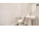 Clean, modern half-bathroom featuring pedestal sink, round mirror and neutral color palette at 10026 Honey Rose Ave, Las Vegas, NV 89143